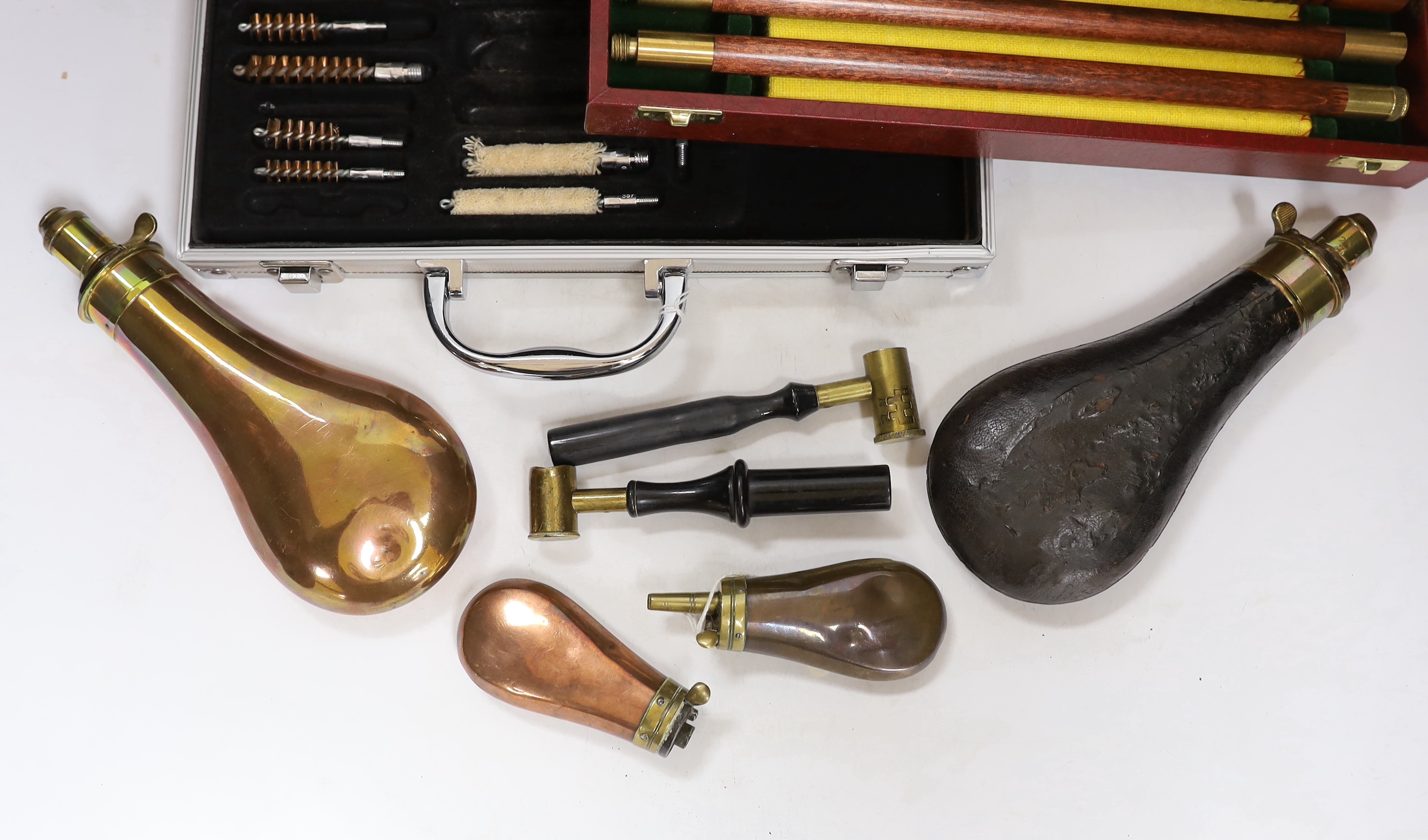 Three copper powder flasks, a leather powder flask, two powder measures and two cases of cleaning tools